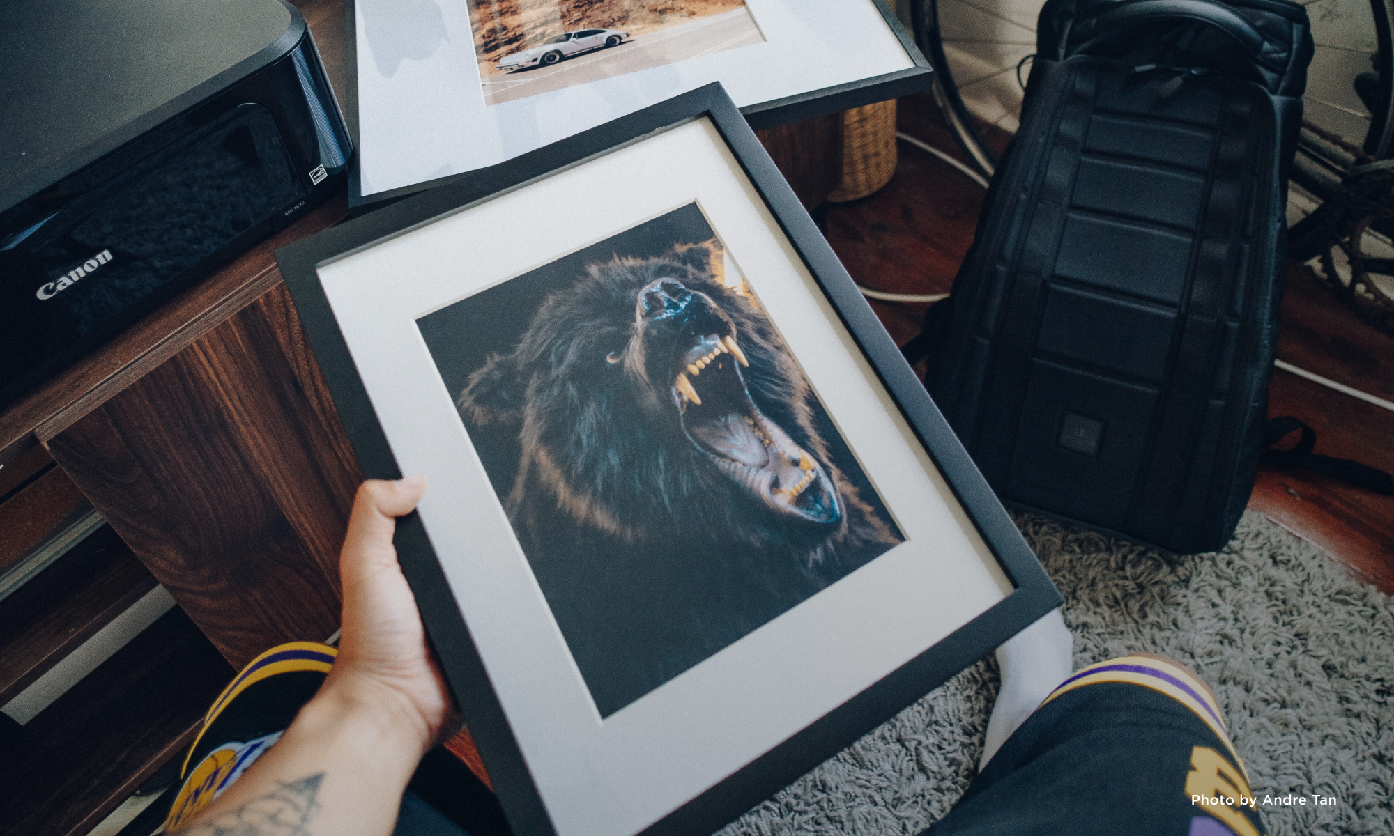 Hand holding a framed photo of a roaring bear.